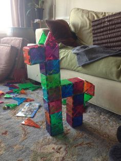 a colorful wooden cross sitting on the floor next to a couch