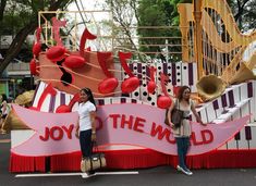 two women standing in front of a sign that says joy to the world