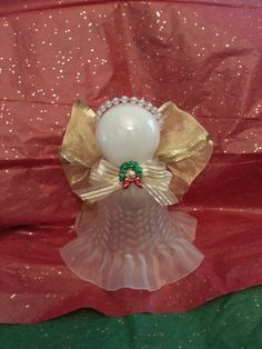 a white vase with a bow on it sitting on a red and green table cloth