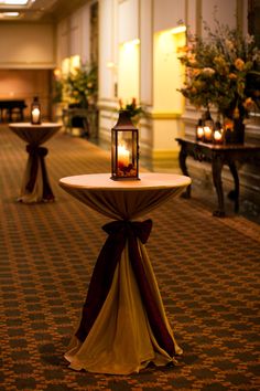 two tables with candles on them in the middle of a room