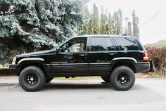 a black jeep is parked in front of some trees