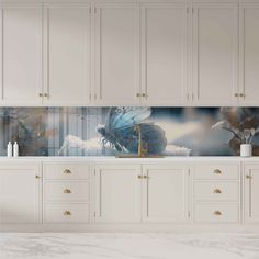 a kitchen with marble counter tops and white cabinets, painted butterflies on the backsplash