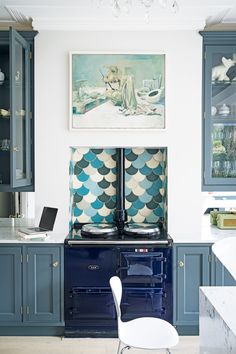 a blue stove top oven sitting inside of a kitchen next to a painting on the wall