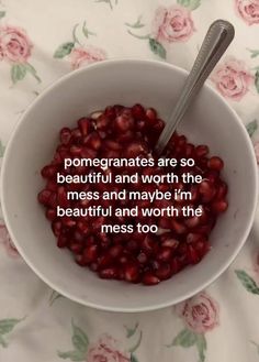 a bowl filled with pomegranates on top of a floral table cloth