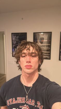 a young man with curly hair wearing a t - shirt and looking at the camera