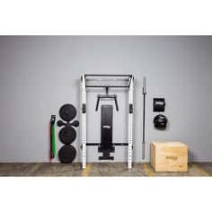 a home gym equipment set up against a gray wall with two squat racks and one barbell