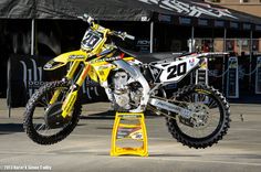 a yellow dirt bike parked on top of a metal stand