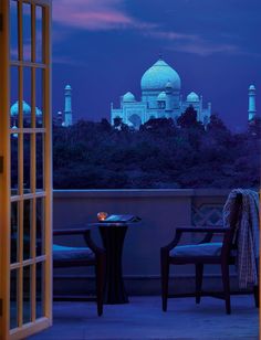 a view of the taj mahal from an outside room at night with two chairs and a table