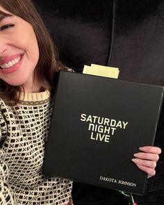 a woman holding up a book that says saturday night live