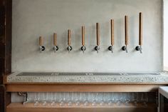 a row of wine glasses sitting on top of a wooden shelf next to a wall