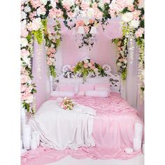 a bed covered in pink flowers and greenery next to a chandelier filled with candles