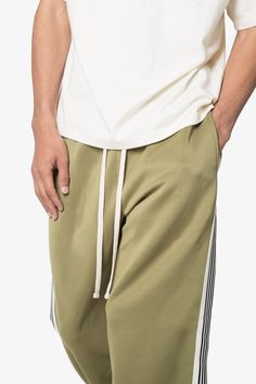 the Relaxed Tricot Track Pants are designed with a custom-developed, 300 GSM single-layer tricot fabric, featuring a contrasting striped panel down the side leg and an extended drawcord details relaxed fit 65% polyester 35% cotton custom developed heavyweight tricot fabric model is 6’1, 160 lbs and wears a size medium Green Bottoms With Side Stripes For Streetwear, Green Sweatpants With Side Stripes For Streetwear, Green Side Stripe Pants For Streetwear, Green Streetwear Pants With Side Stripes, Green Pants With Side Stripes For Streetwear, Spring Cotton Sweatpants With Side Stripes, Cotton Joggers With Side Stripes, Wide Leg Cotton Pants With Contrast Stripes, Green Athleisure Bottoms With Side Stripes