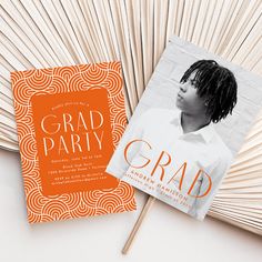 an orange and white graduation party card on top of a fan with the word grad party printed on it