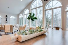 a living room filled with lots of windows and wooden furniture next to a large window