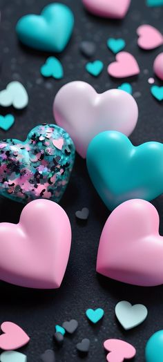 several heart shaped candies on a black surface with confetti scattered around them