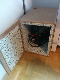 a cat is sitting in the corner of a small room with its head sticking out