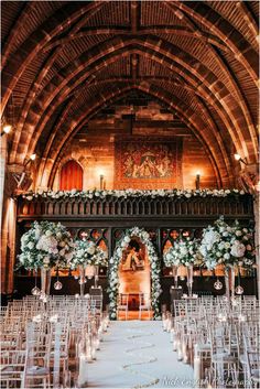 an indoor wedding venue with rows of chairs and floral arrangements on the aisle, along with candles