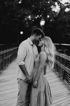 a man and woman standing on a bridge kissing