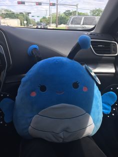 a blue stuffed animal sitting in the driver's seat of a car with its head up