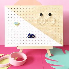 two pairs of earrings sitting on top of a pegboard next to a pair of earring holders