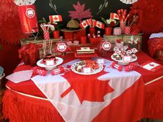 the table is set up with red and white decorations, including candy bars, cupcakes, and candies