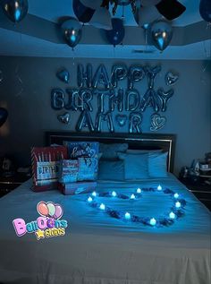 a bed with blue lights on it in a room filled with balloons and gifts for the birthday boy