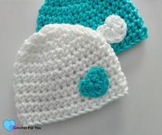 two crocheted hats sitting on top of a white table next to each other