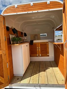 the inside of a trailer with wood flooring and white appliances on it's side