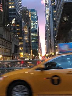 a yellow taxi driving down a street next to tall buildings in the city at night