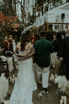 a bride and groom walking down the aisle at their outdoor wedding ceremony with candles in front of them