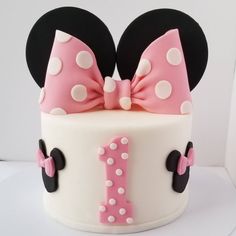 a minnie mouse cake is decorated with pink and white polka dots, black ears, and a bow