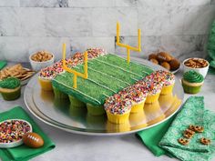 a football field cake with sprinkles and cupcakes on the side