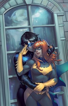 two people dressed as batman and batgirl standing in front of a window with their arms around each other