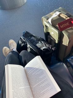 an open book sitting on top of a blue floor next to two pieces of luggage