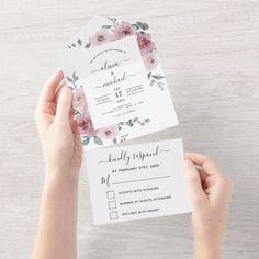 two hands holding wedding cards with flowers on them