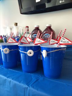 blue plastic buckets with red and white straw flags tied to them sitting on a table