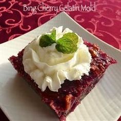 a piece of cake on a white plate with whipped cream and mint sprig