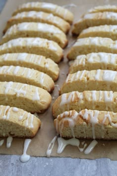 a bunch of cookies that are sitting on a piece of parchment paper with icing