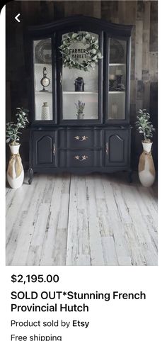 a black china cabinet sitting on top of a wooden floor next to two vases