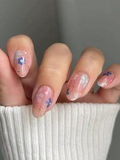 a woman's hand with pink and blue flowers on it, holding onto a white sweater