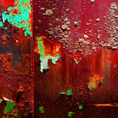 an old rusted metal surface with green and red paint