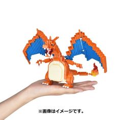 a hand holding an orange and blue lego dragon with it's wings spread out