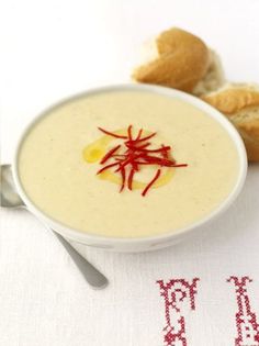 a white bowl filled with soup next to some bread