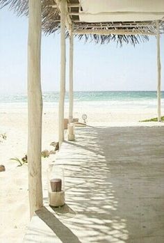 an empty beach covered in white umbrellas next to the ocean