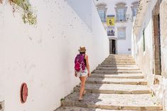 a woman is walking up some steps in the sun with a backpack on her back