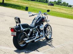 a black motorcycle parked in a parking lot next to a grassy area with trees and grass behind it