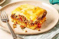 a piece of lasagna on a plate next to a fork and napkin with utensils