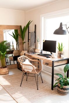 a desk with a computer, chair and potted plants