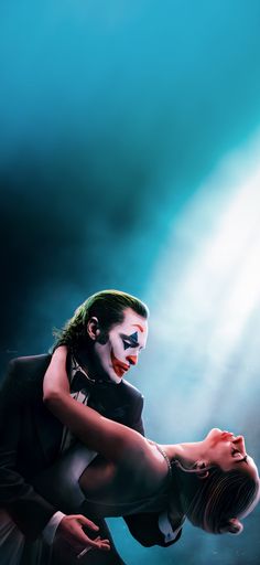 a man dressed as the joker is performing on stage with his hands behind his head