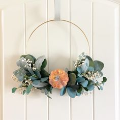 a wreath with flowers and greenery hangs on the wall